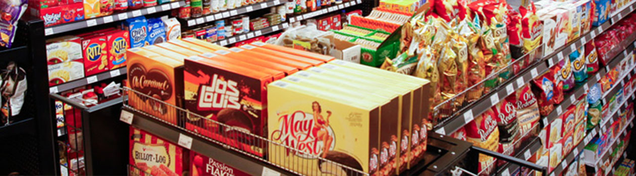 A banner photograph of the filled aisles within a Needs store showing familiar confectionary brands such as Ritz and May West.